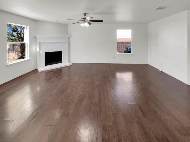 unfurnished living room featuring a brick fireplace, dark hardwood / wood-style floors, and ceiling fan