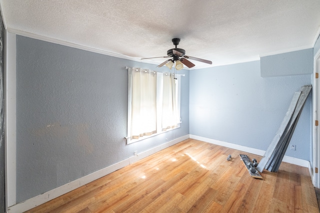 empty room featuring crown molding, wood-type flooring, a textured ceiling, and ceiling fan