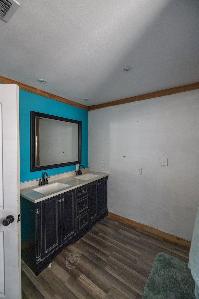 bathroom featuring vanity, wood-type flooring, a textured ceiling, and ornamental molding