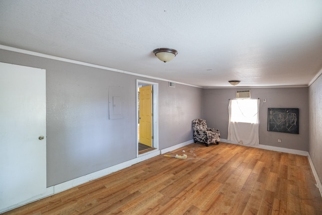 empty room featuring crown molding, electric panel, and hardwood / wood-style flooring