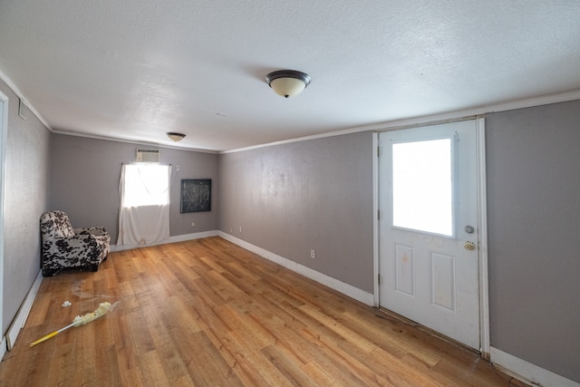 entryway featuring ornamental molding, light hardwood / wood-style flooring, and a textured ceiling