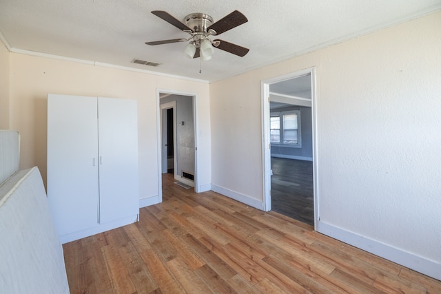 unfurnished bedroom featuring a closet, crown molding, light wood-type flooring, and ceiling fan