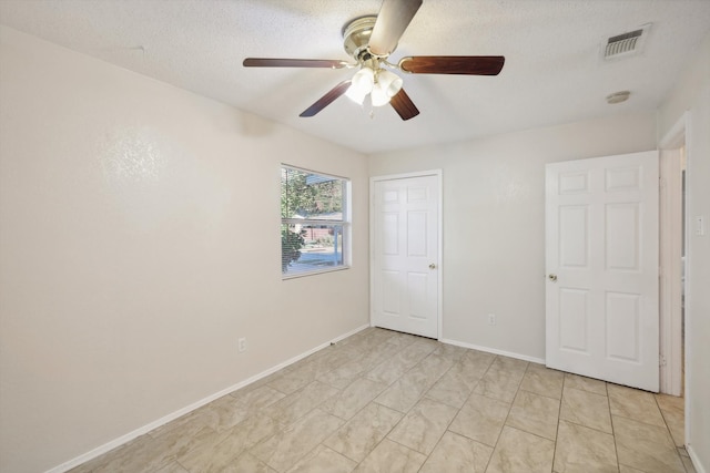 unfurnished bedroom with ceiling fan and a textured ceiling