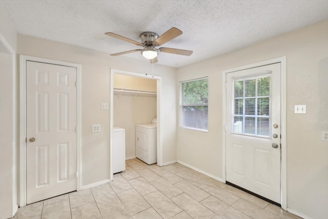 interior space featuring ceiling fan, washer and clothes dryer, light tile patterned floors, and a textured ceiling