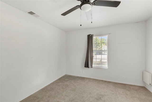 unfurnished room with radiator heating unit, light colored carpet, and ceiling fan