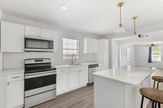 820 Allen St, Denton, TX 76205 - kitchen featuring a breakfast bar area, backsplash, light wood-type flooring, a sink, and stainless steel appliances