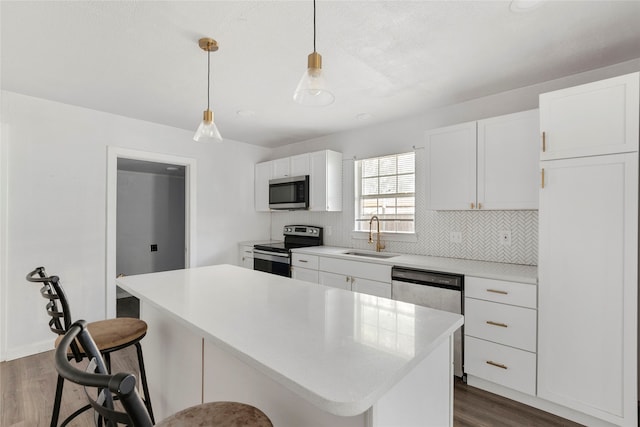 kitchen featuring dark wood-type flooring, hanging light fixtures, stainless steel appliances, a center island, and white cabinets