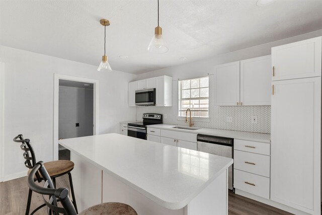 820 Allen St, Denton, TX 76205 - kitchen with appliances with stainless steel finishes, a sink, a kitchen bar, a kitchen island, and dark wood-style floors