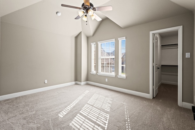 unfurnished bedroom featuring light carpet, ceiling fan, lofted ceiling, a walk in closet, and a closet