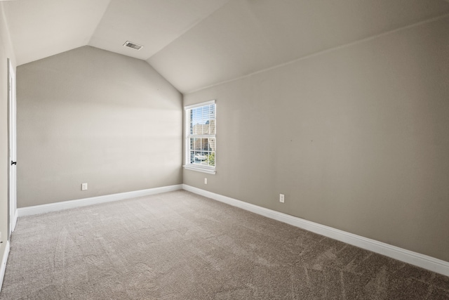 carpeted empty room featuring vaulted ceiling