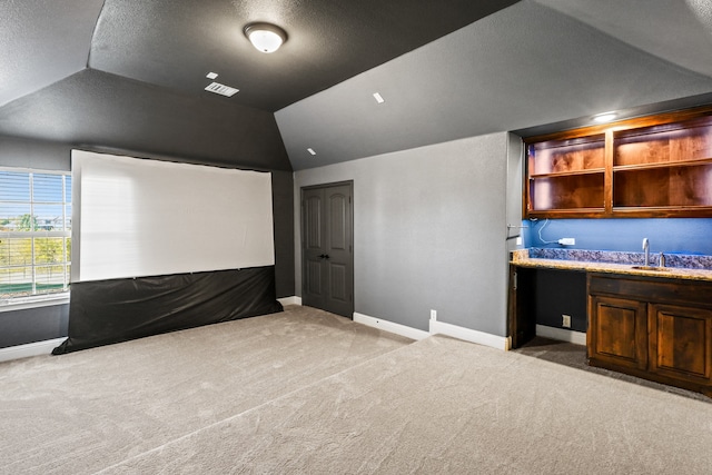 home theater with sink, a textured ceiling, light carpet, and vaulted ceiling