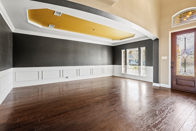 spare room featuring dark hardwood / wood-style floors, a tray ceiling, crown molding, and a notable chandelier