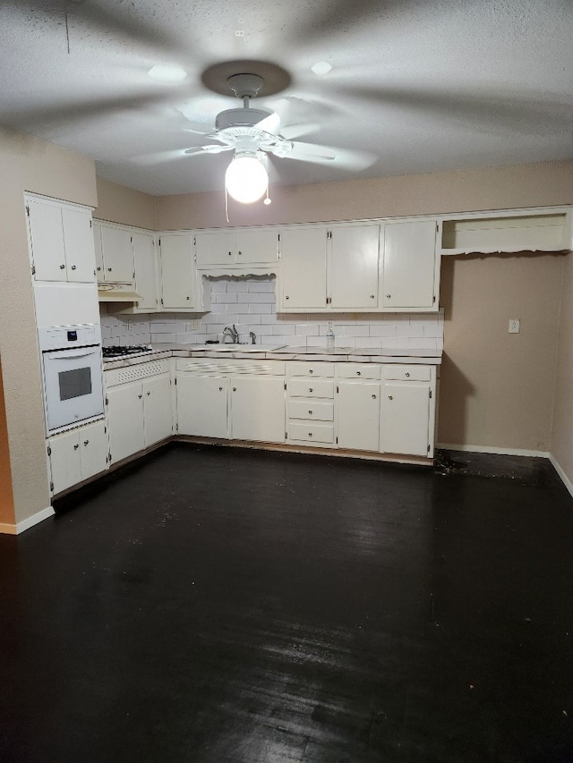 kitchen featuring oven, decorative backsplash, white cabinets, and gas stovetop