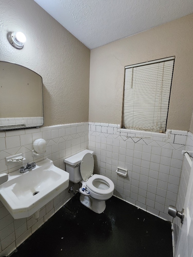 bathroom with tile walls, sink, a textured ceiling, and toilet