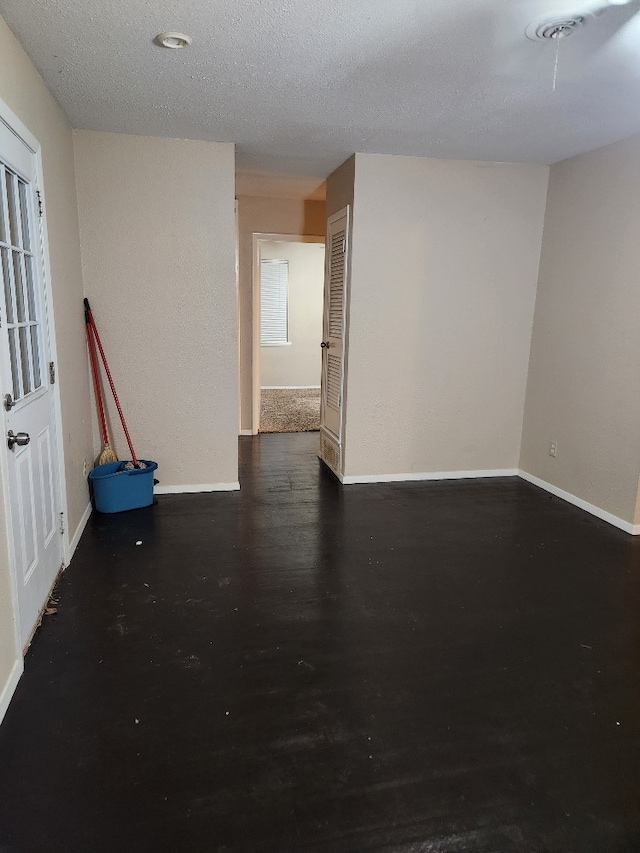 unfurnished room featuring a textured ceiling and dark hardwood / wood-style flooring