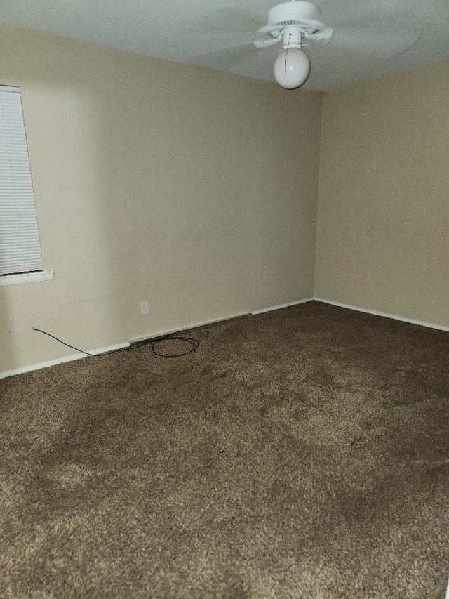carpeted empty room with baseboards and a ceiling fan
