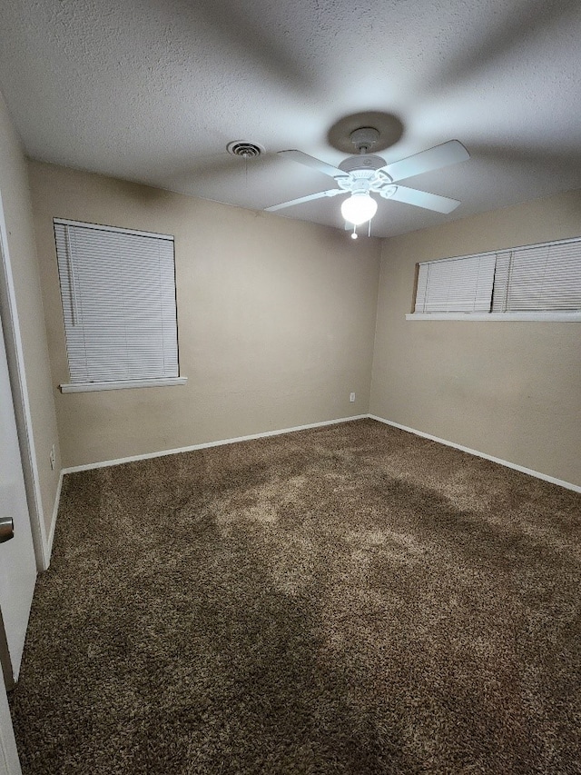 spare room featuring visible vents, baseboards, ceiling fan, a textured ceiling, and carpet