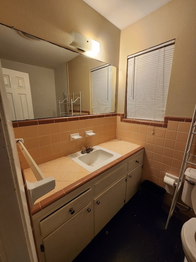 bathroom featuring toilet, tile walls, wainscoting, and vanity