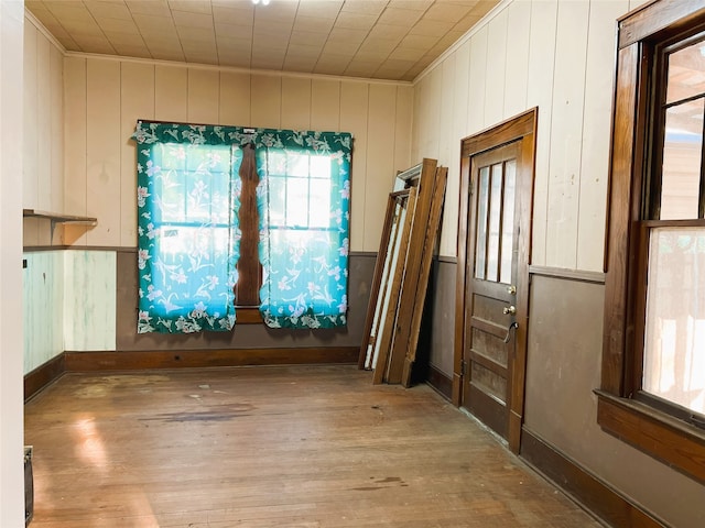 spare room with wooden walls, wood finished floors, crown molding, and baseboards