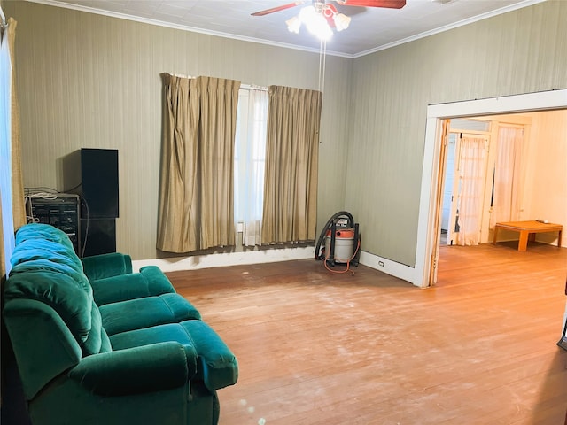 sitting room with a ceiling fan, wood finished floors, and crown molding