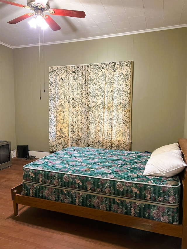 bedroom featuring wood finished floors, a ceiling fan, and ornamental molding