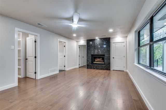 unfurnished living room with hardwood / wood-style floors, a high end fireplace, and ceiling fan