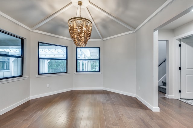 empty room featuring hardwood / wood-style flooring, an inviting chandelier, vaulted ceiling, and ornamental molding