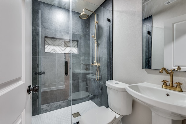 bathroom with a shower with shower door, sink, and toilet