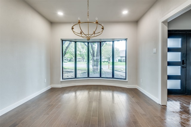 spare room with a chandelier and wood-type flooring