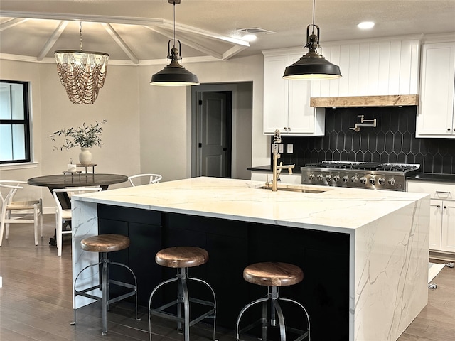 10544 Cox Ln, Dallas, TX 75229 - kitchen featuring backsplash, wood finished floors, white cabinets, a center island with sink, and recessed lighting
