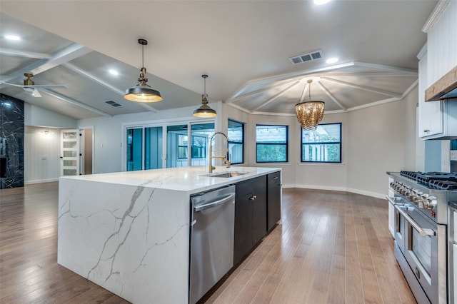 kitchen with vaulted ceiling with beams, a center island with sink, stainless steel appliances, pendant lighting, and sink