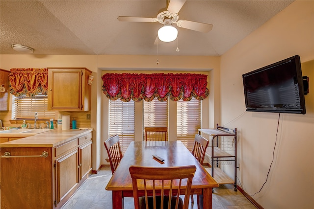 dining area featuring ceiling fan, a textured ceiling, and sink