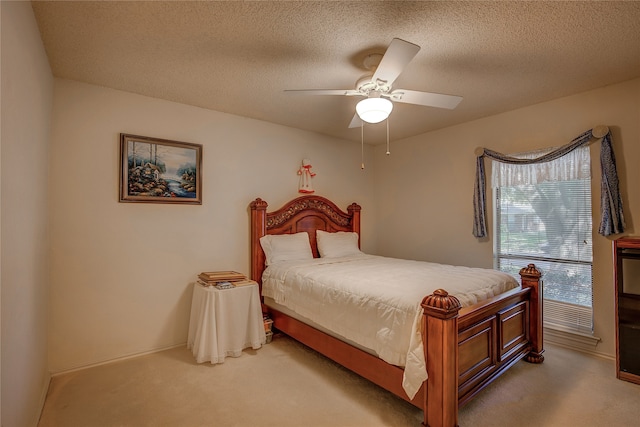 bedroom featuring a textured ceiling, light colored carpet, and ceiling fan