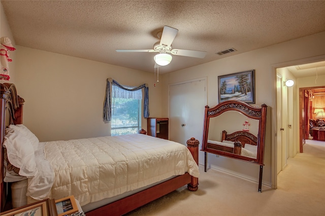 bedroom with a closet, ceiling fan, light carpet, and a textured ceiling