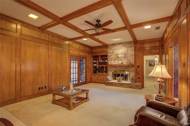 living room with french doors, wood walls, beamed ceiling, and a brick fireplace