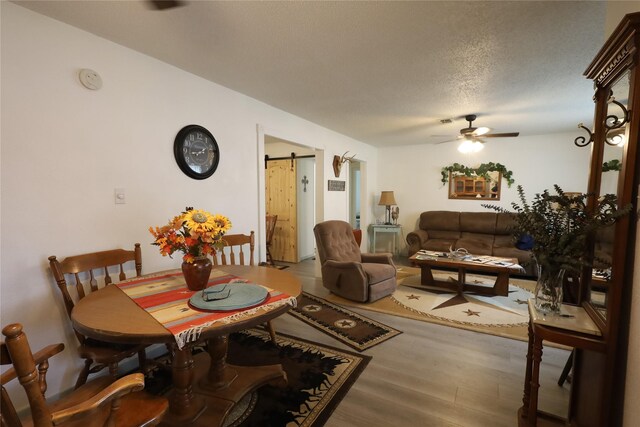 4240 Cheyenne Dr, May, TX 76857 - dining room with a barn door, a textured ceiling, ceiling fan, and wood finished floors