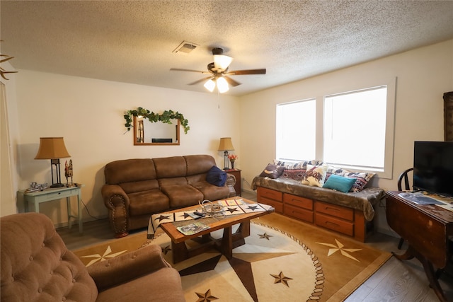 living room featuring a textured ceiling, wood-type flooring, and ceiling fan