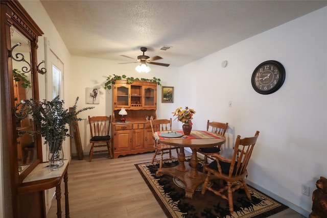 dining area featuring light hardwood / wood-style flooring, a textured ceiling, and ceiling fan