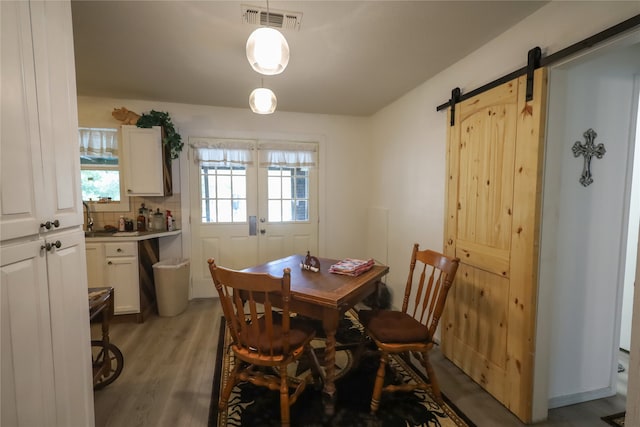 dining space featuring light hardwood / wood-style floors, a barn door, and a healthy amount of sunlight