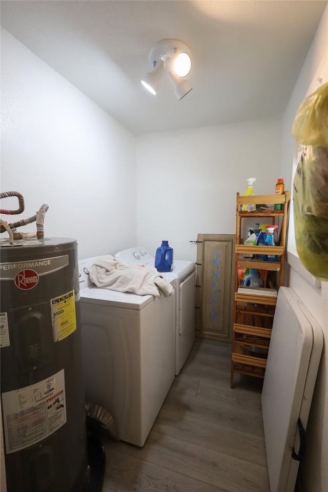 clothes washing area with water heater, washing machine and dryer, and dark hardwood / wood-style flooring