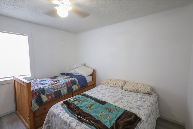 bedroom featuring hardwood / wood-style floors, a textured ceiling, and ceiling fan