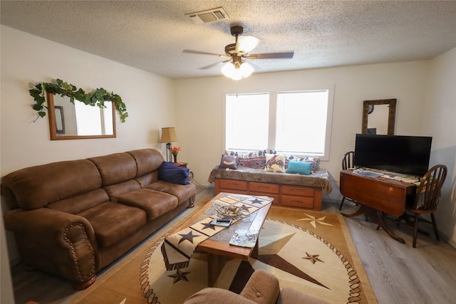 living room with ceiling fan, a textured ceiling, and light hardwood / wood-style flooring