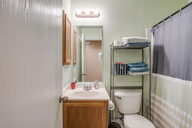 bathroom featuring curtained shower, vanity, and toilet