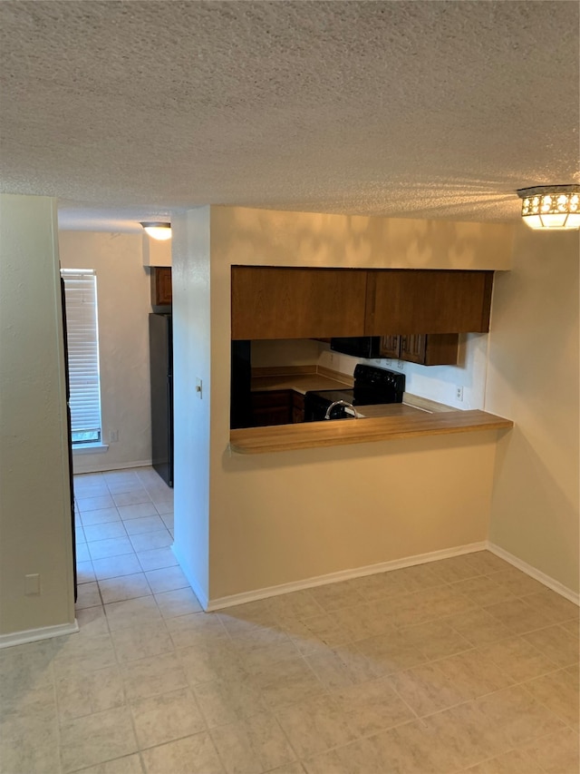 kitchen featuring black range with electric stovetop, light tile patterned flooring, a textured ceiling, kitchen peninsula, and stainless steel fridge