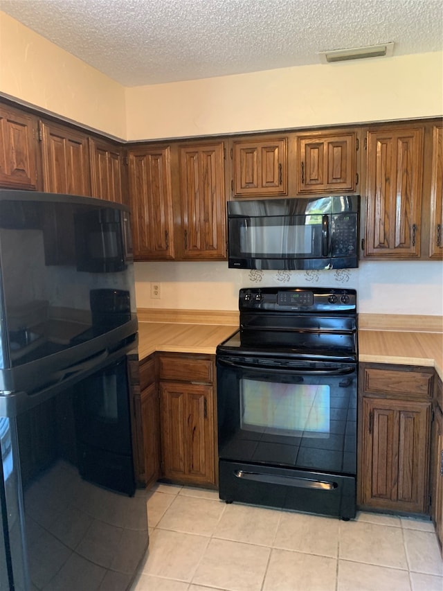 kitchen with black appliances, a textured ceiling, and light tile patterned floors