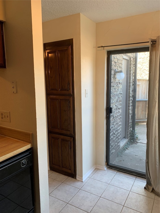 doorway to outside featuring a textured ceiling and light tile patterned floors