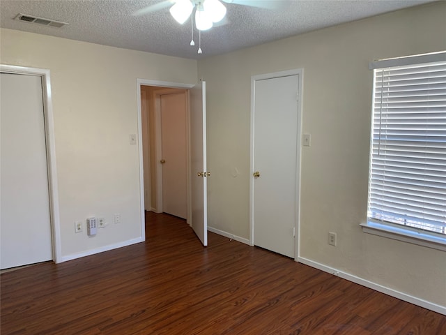 unfurnished bedroom featuring dark hardwood / wood-style floors, a textured ceiling, and ceiling fan