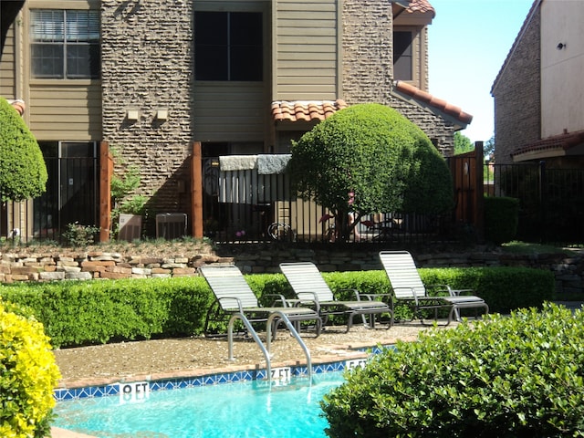 back of house featuring cooling unit and a fenced in pool