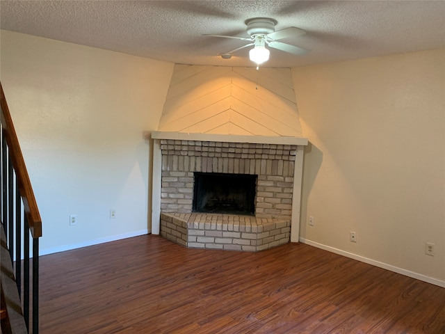 unfurnished living room featuring a fireplace, a textured ceiling, dark hardwood / wood-style floors, and ceiling fan