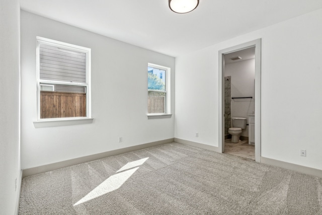 unfurnished bedroom featuring ensuite bathroom and light colored carpet